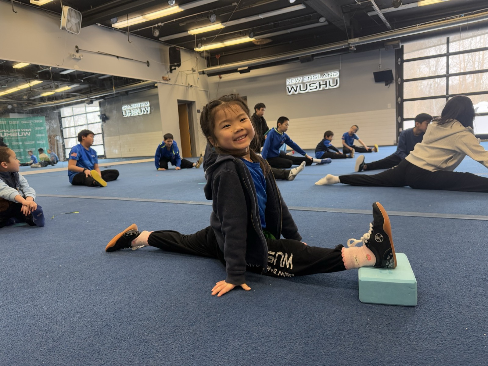 A young student smiles in the splits