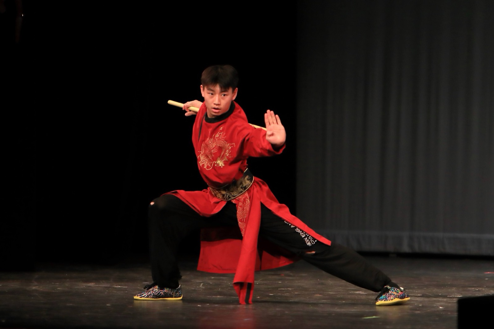 A performer in red holds a stance on stage