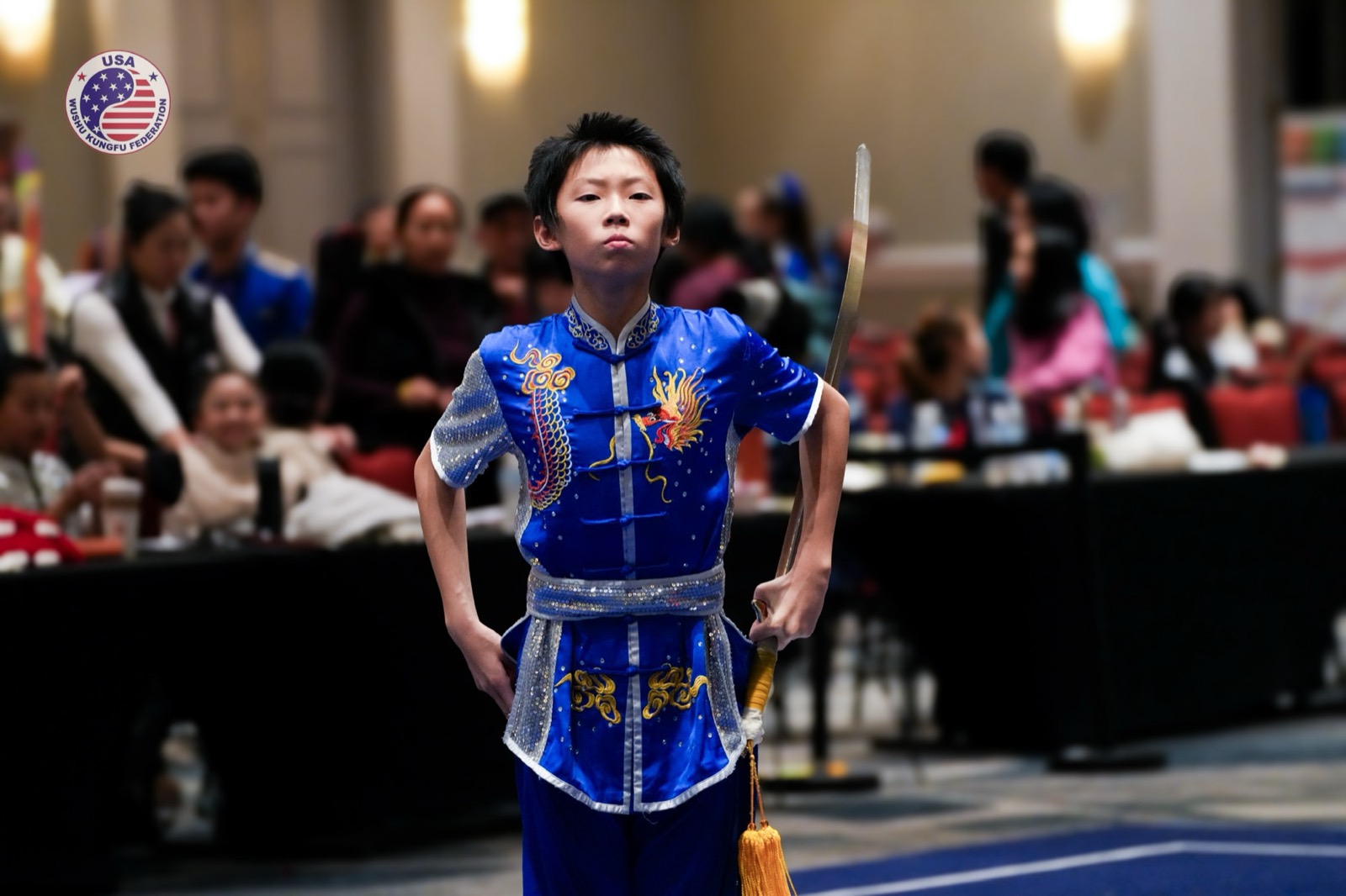 A competitor with a broadsword stands ready on the carpet